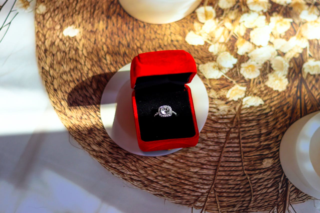 A close up of a white gold halo diamond engagement ring glistening in sunlight on top of the table.