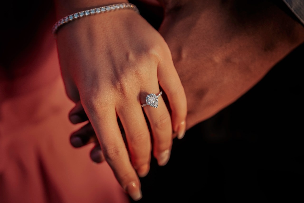 A close-up of a woman’s hand adorned with white gold pear shaped engagement ring.