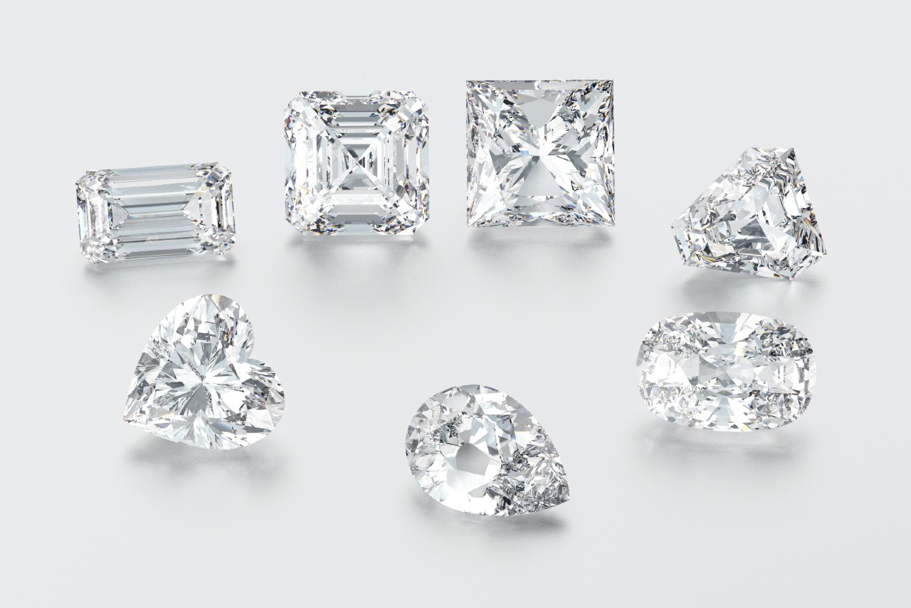 seven diamonds in different cuts on a white surface