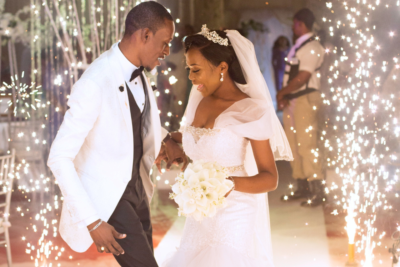 A couple dancing at their wedding reception with sparkling lights and fireworks happening around them.