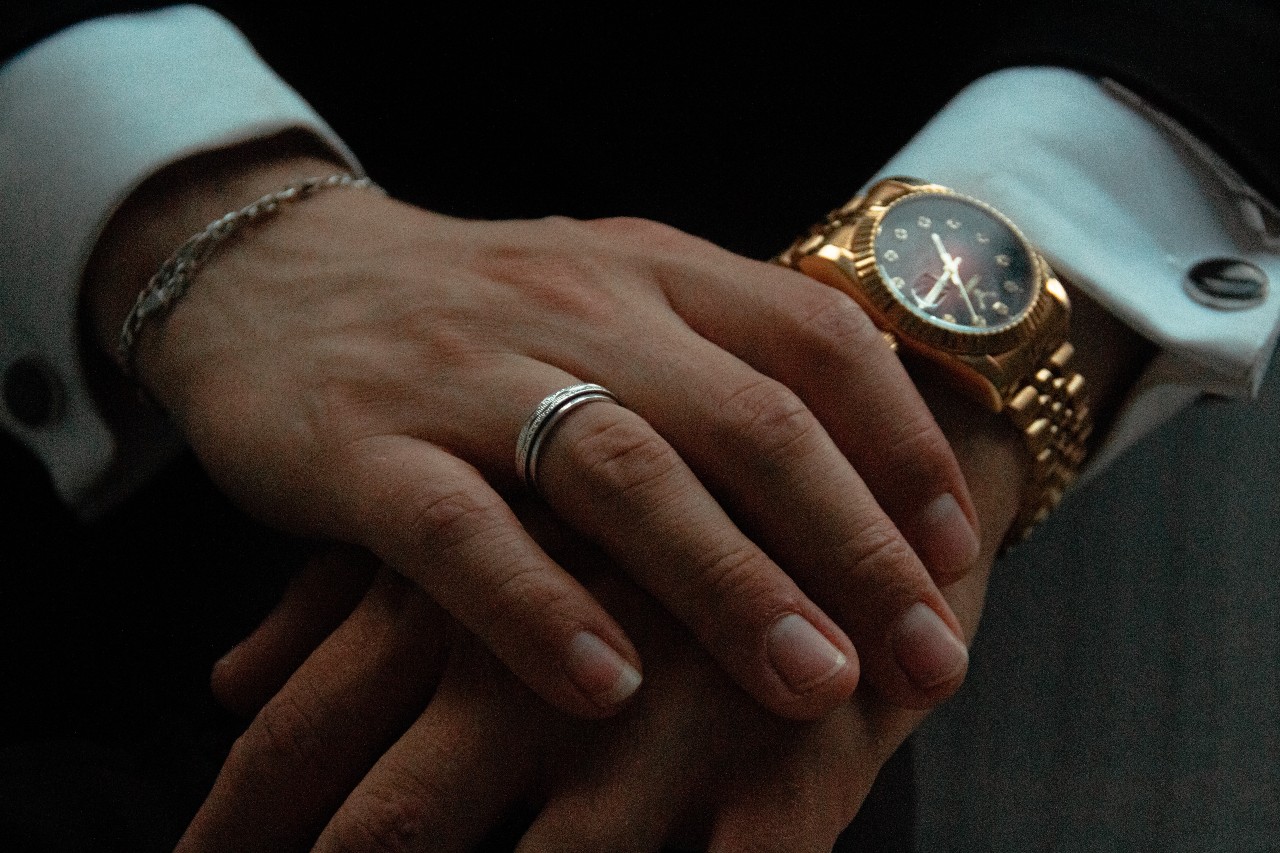 a man’s hands crossed over each other, wearing a yellow gold watch