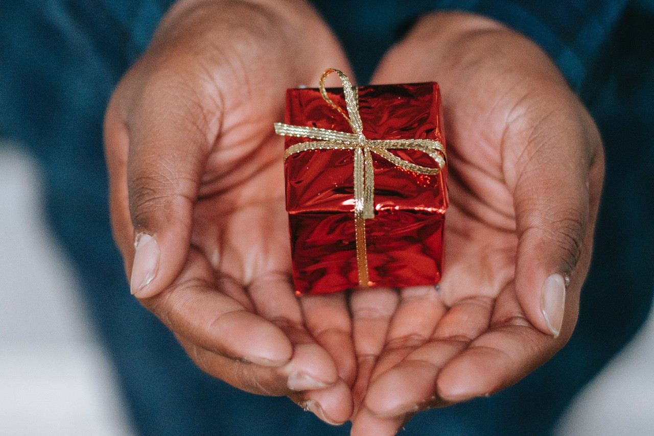 A small red gift box on a person’s palms.