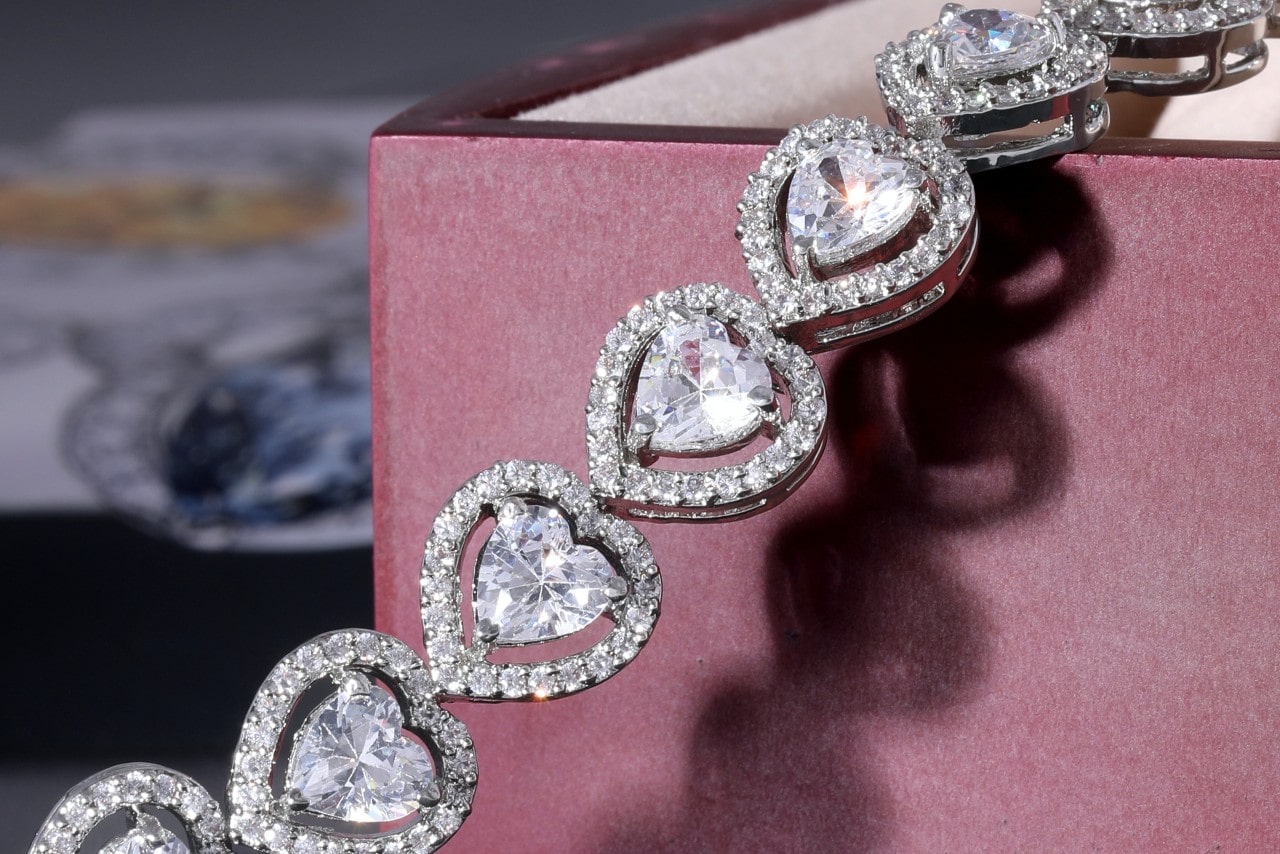 A diamond heart bracelet draped across a red box.