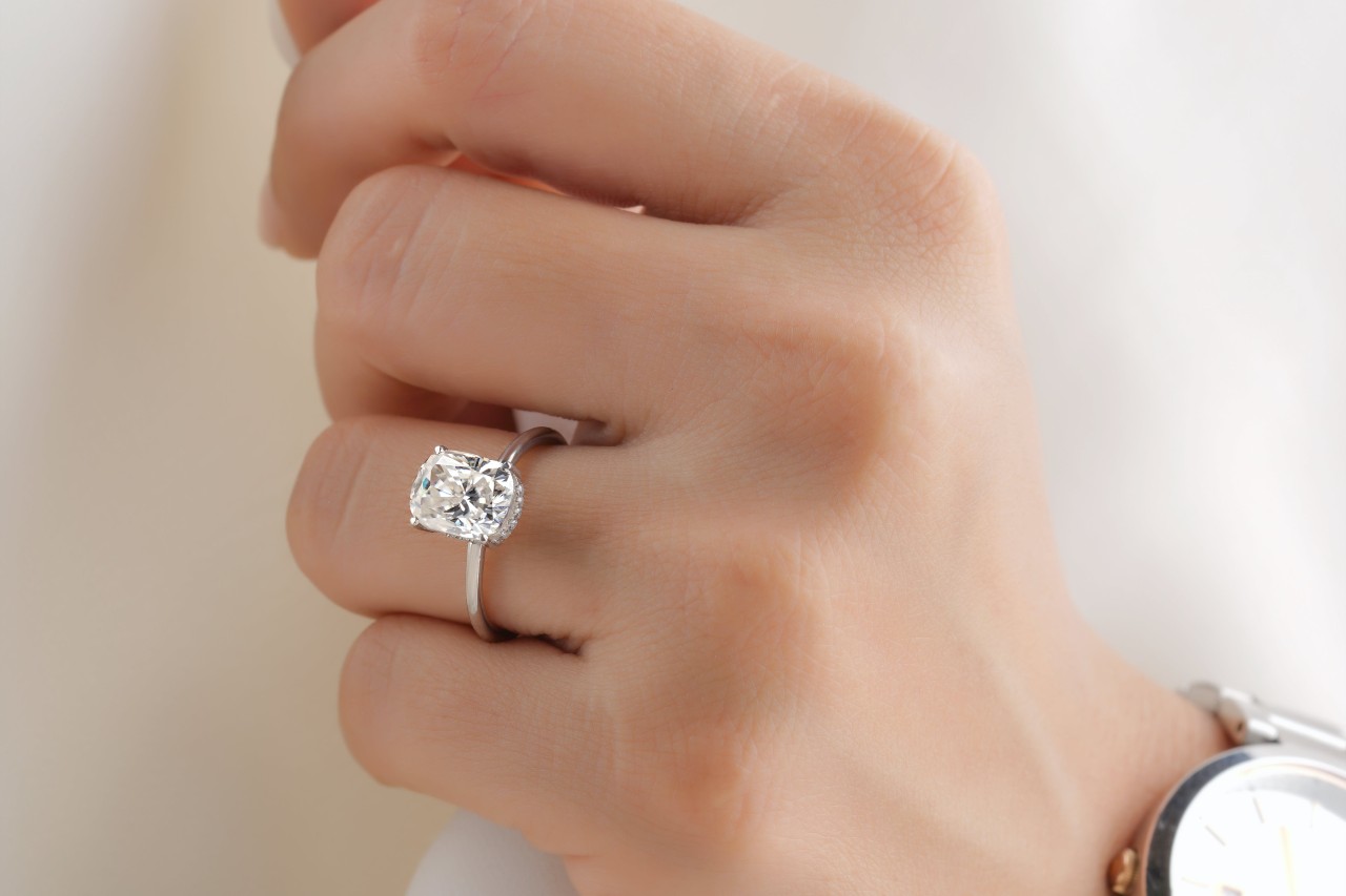 close up image of a hand wearing a solitaire engagement ring with a white gold setting