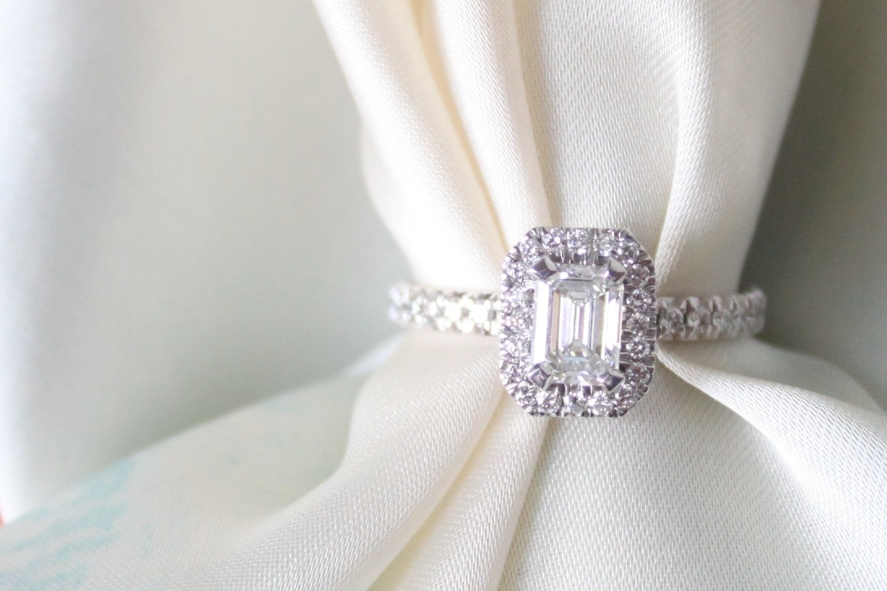 a white gold halo engagement ring with a piece of white fabric threaded through