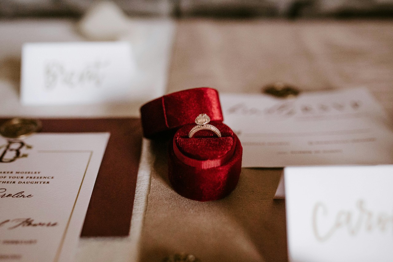 an engagement ring in a red ring box on a table set for a wedding