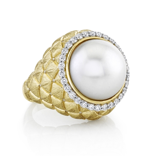 A yellow gold ring with a quilted texture, featuring a large central pearl