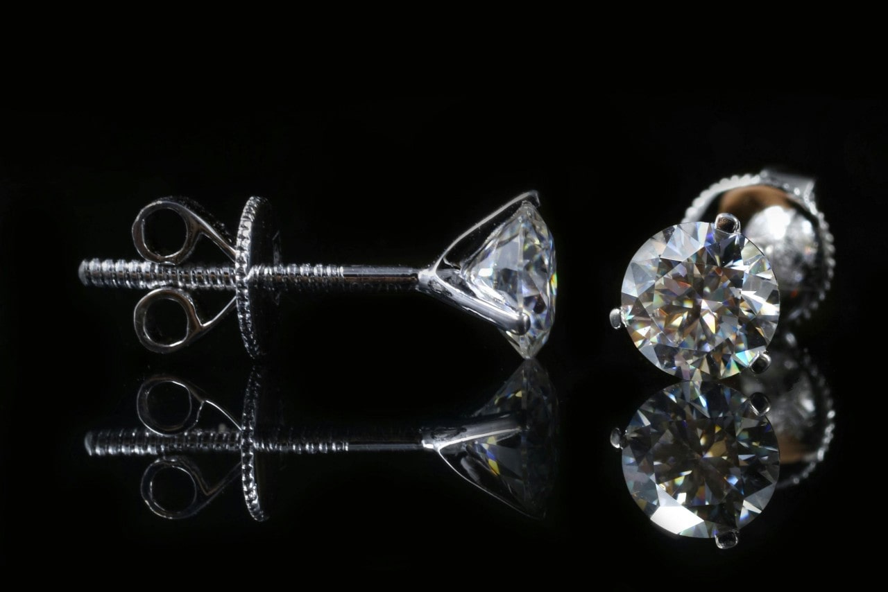 White gold diamond studs on a black background.