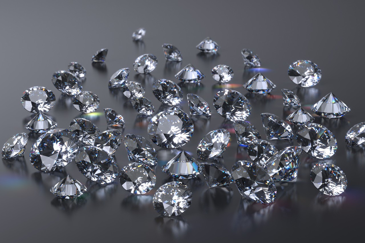 A collection of sparkling diamonds scattered on a glossy surface. A collection of sparkling diamonds scattered on a glossy surface.