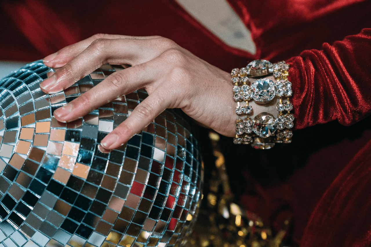 A hand with a diamond bracelet on top of a mirror ball. A hand with a diamond bracelet on top of a mirror ball.