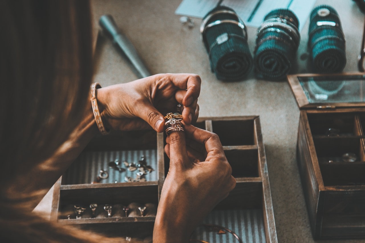 A close up of a person picking several rings from a wooden jewelry box. A close up of a person picking several rings from a wooden jewelry box.