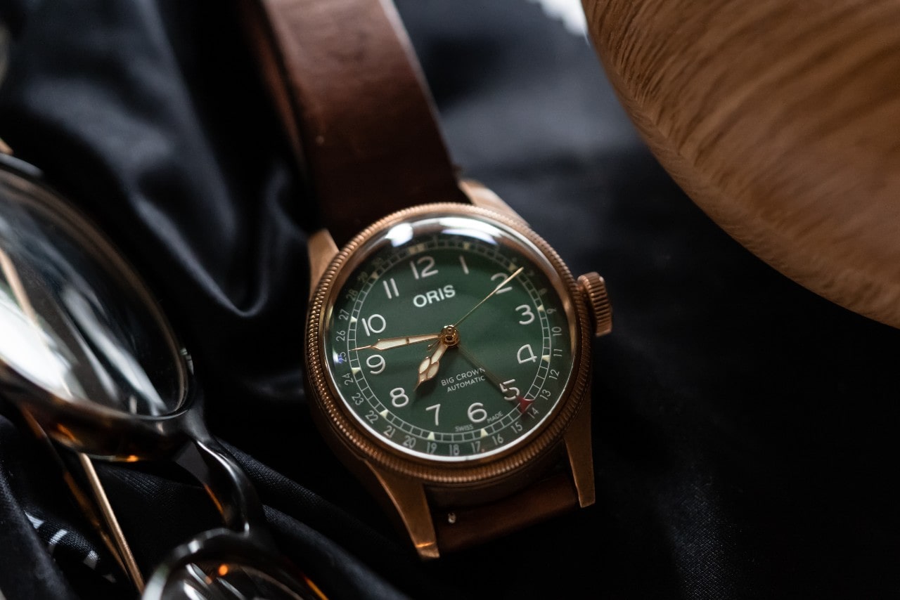 an Oris watch resting next to a pair of glasses an Oris watch resting next to a pair of glasses